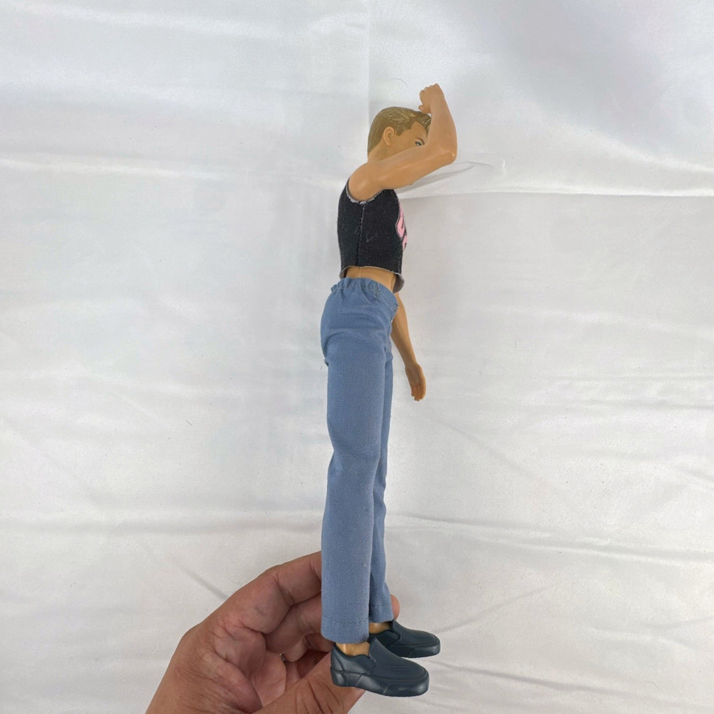 Mattel 12-inch Ken fashion doll with molded blonde hair, blue eyes, graphic sleeveless shirt, and blue trousers