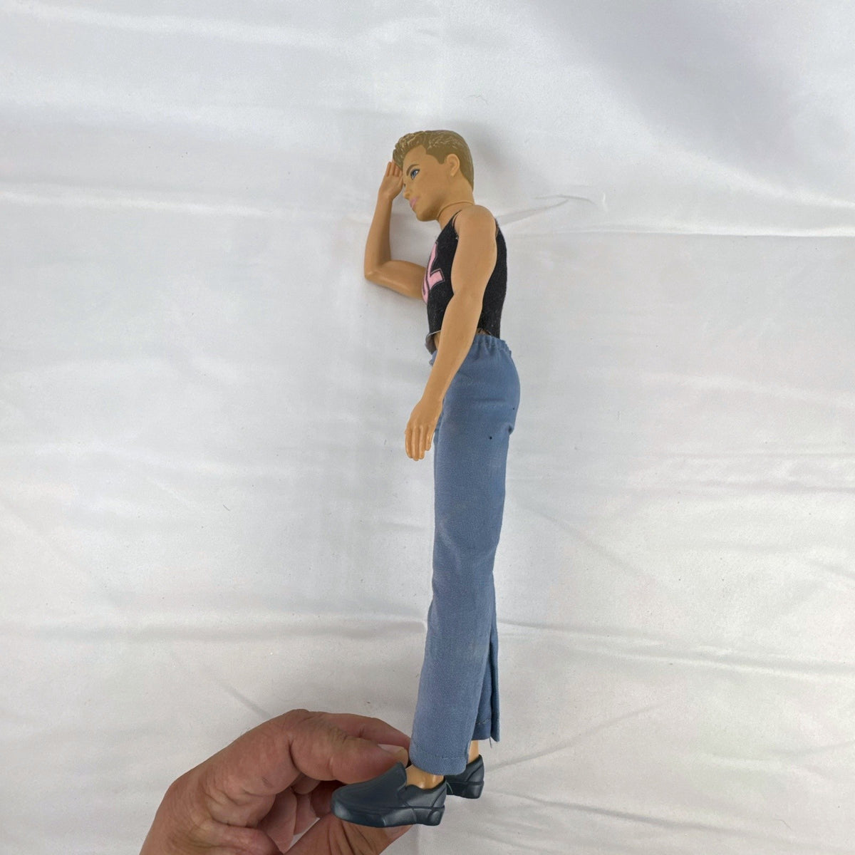Mattel 12-inch Ken fashion doll with molded blonde hair, blue eyes, graphic sleeveless shirt, and blue trousers