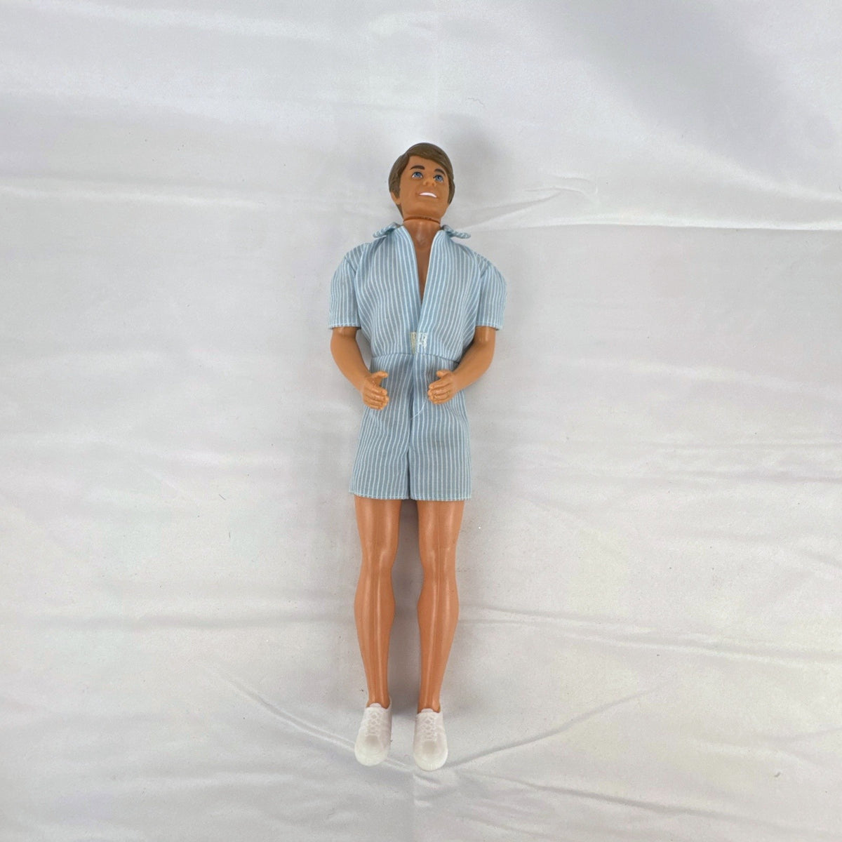 Vintage Mattel Ken 12-inch doll with molded brown hair wearing a blue and white striped romper and white shoes.
