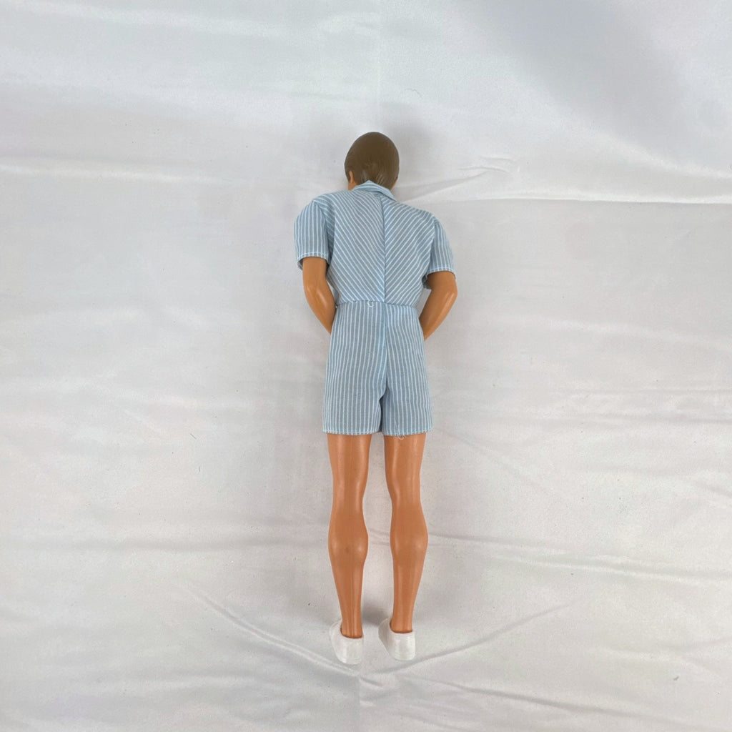 Vintage Mattel Ken 12-inch doll with molded brown hair wearing a blue and white striped romper and white shoes.