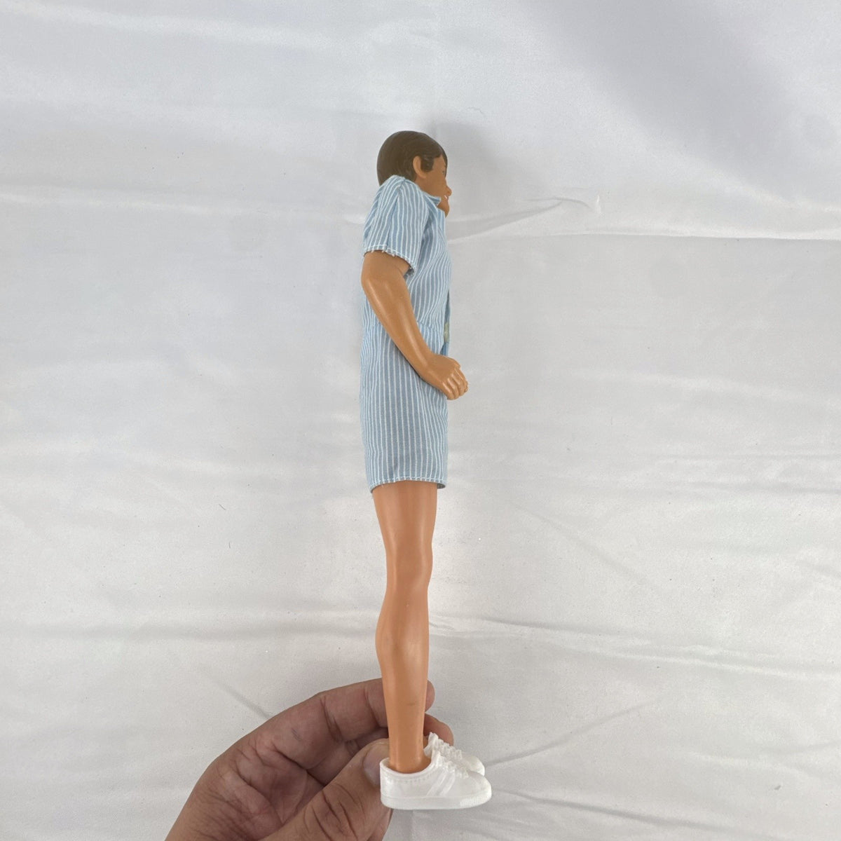 Vintage Mattel Ken 12-inch doll with molded brown hair wearing a blue and white striped romper and white shoes.
