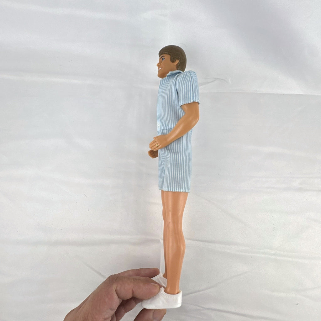 Vintage Mattel Ken 12-inch doll with molded brown hair wearing a blue and white striped romper and white shoes.