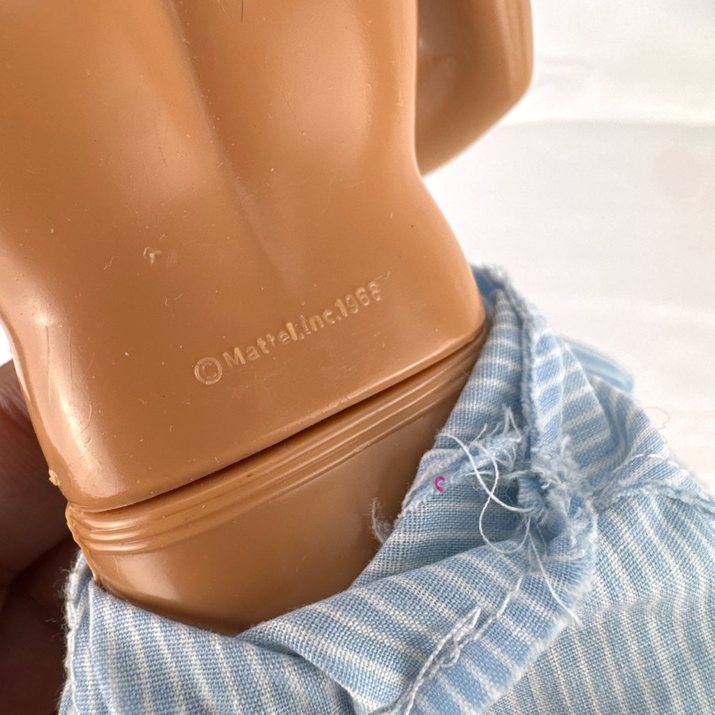Vintage Mattel Ken 12-inch doll with molded brown hair wearing a blue and white striped romper and white shoes.