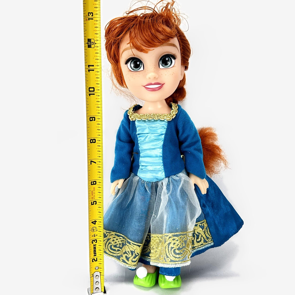 Disney Frozen 13-inch toddler Anna doll wearing blue dress and green pom-pom shoes
