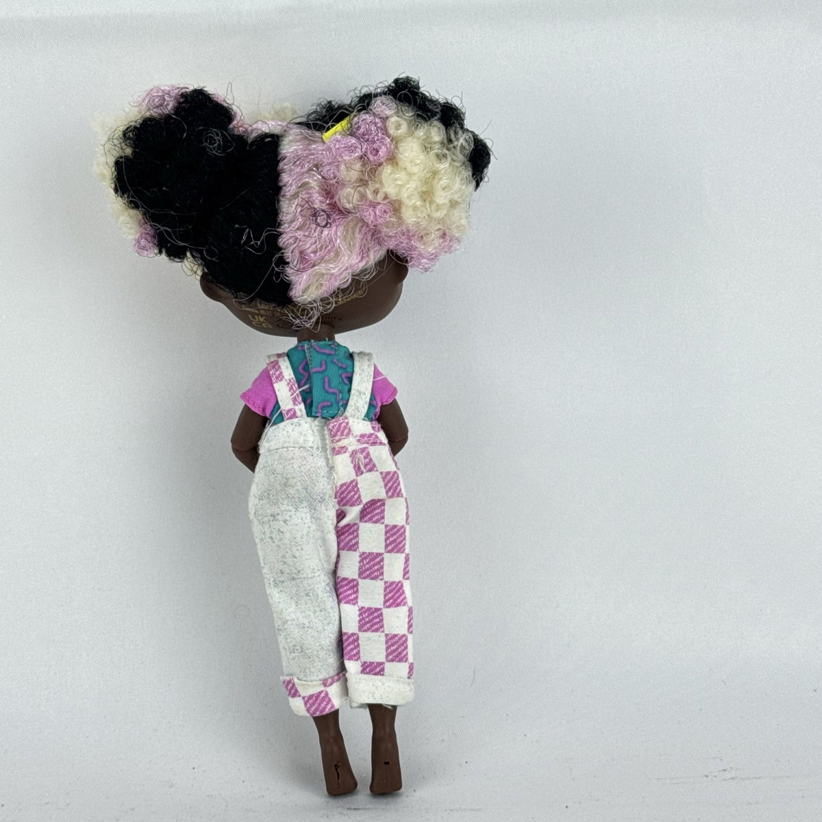 MGA LOL Surprise Tweens Winnie fashion doll in split checkered overalls with two-tone curly afro puff buns.