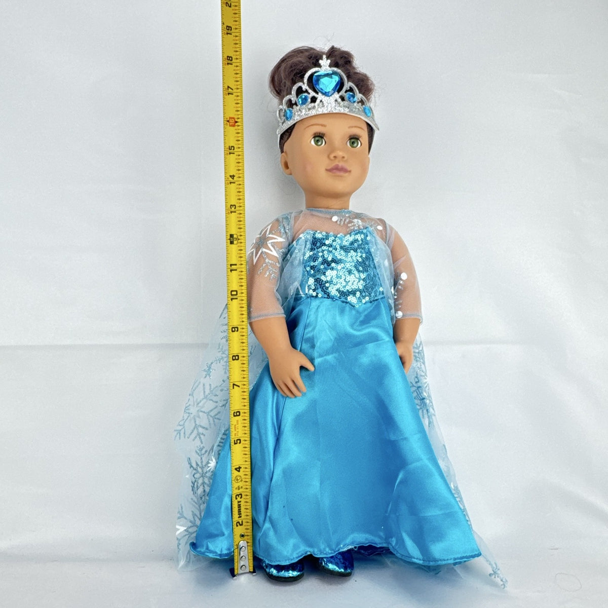 Our Generation 18-inch brunette doll with green eyes wearing a blue sequin ice princess gown and tiara