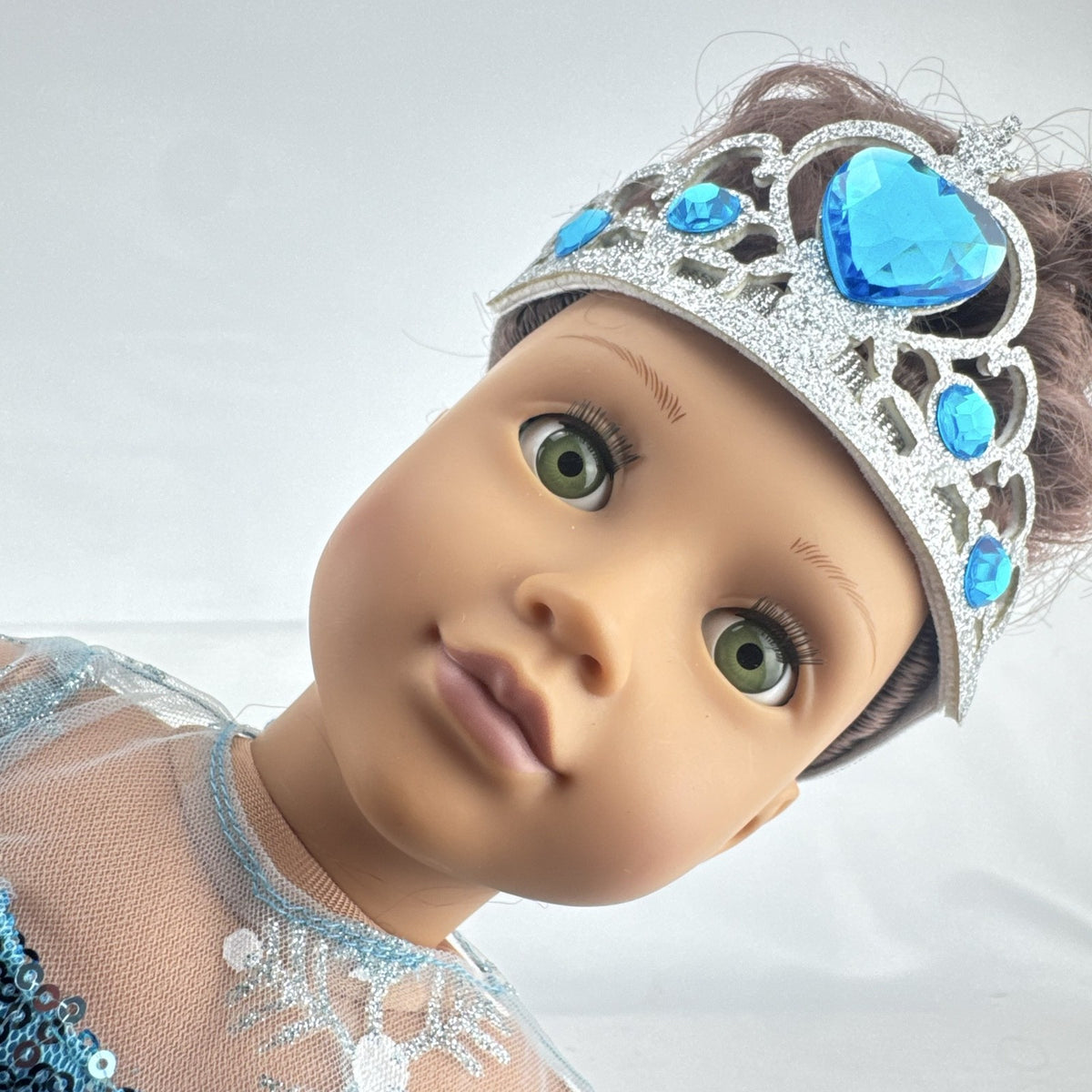 Our Generation 18-inch brunette doll with green eyes wearing a blue sequin ice princess gown and tiara