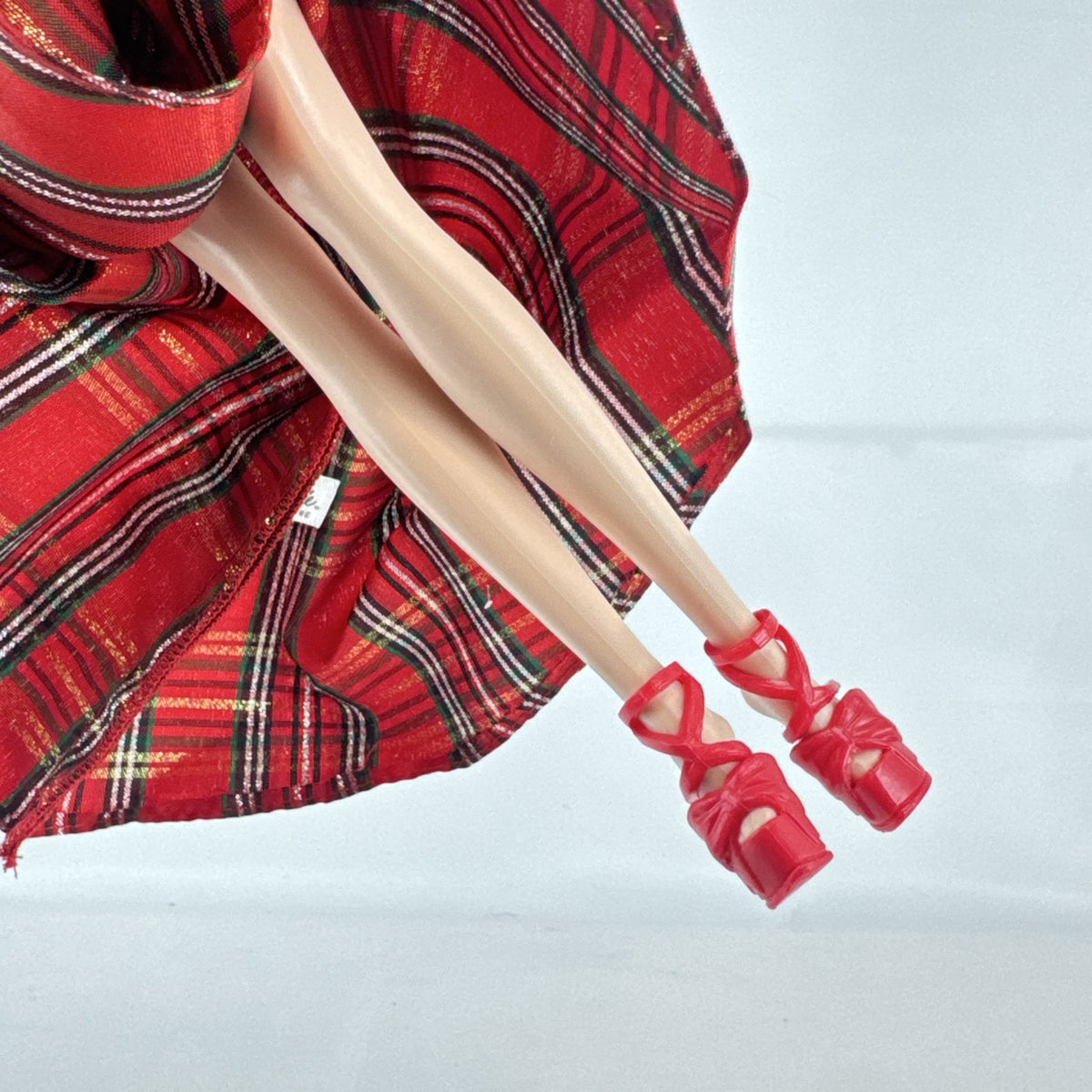 2024 Mattel Holiday Barbie doll wearing an asymmetrical red tartan plaid ball gown with tulle accent