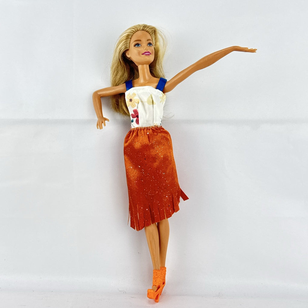 Mattel Barbie fashion doll with blonde hair wearing an orange fringe skirt and floral top