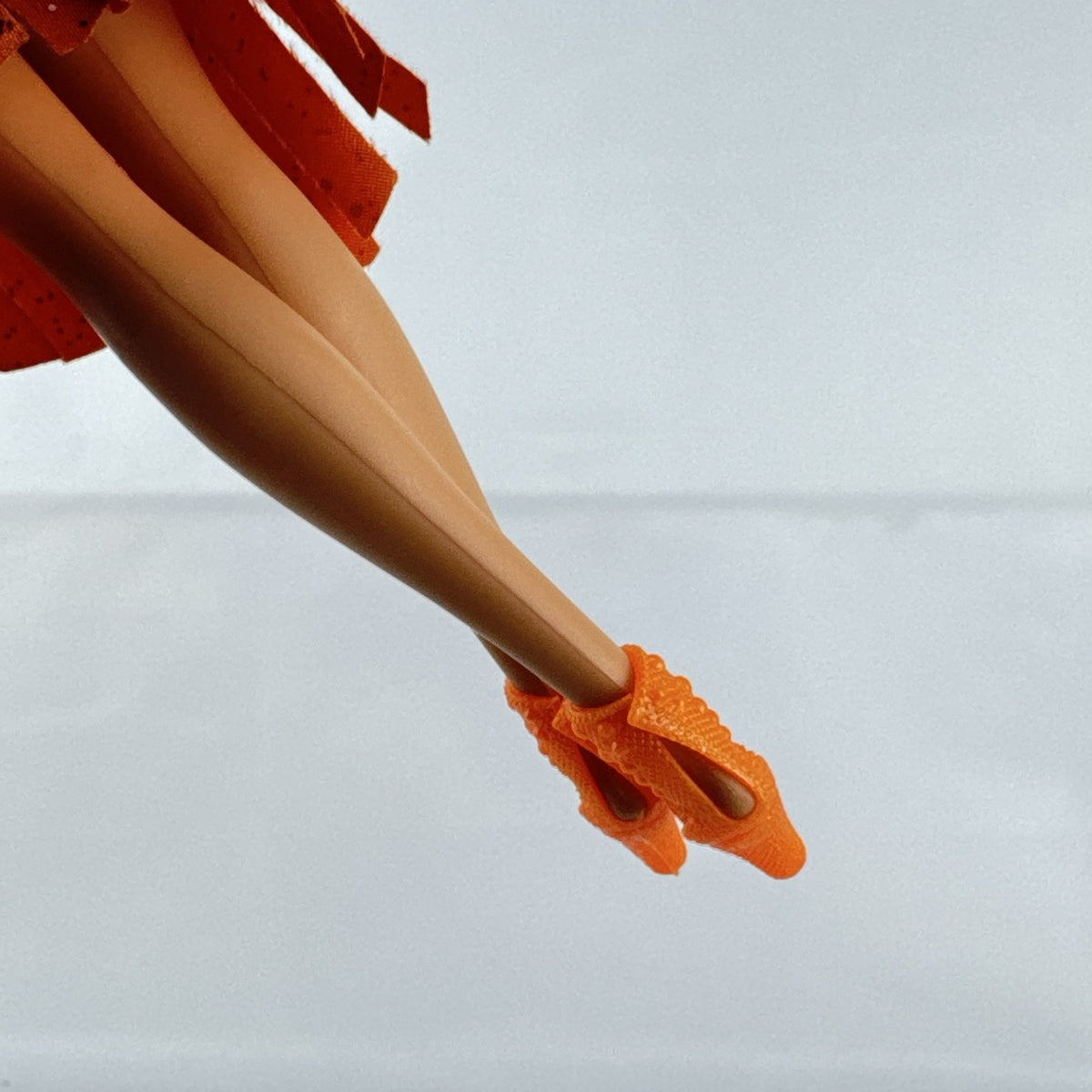 Mattel Barbie fashion doll with blonde hair wearing an orange fringe skirt and floral top