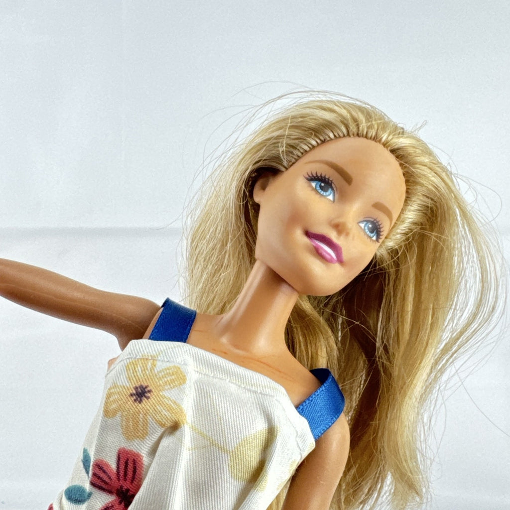 Mattel Barbie fashion doll with blonde hair wearing an orange fringe skirt and floral top