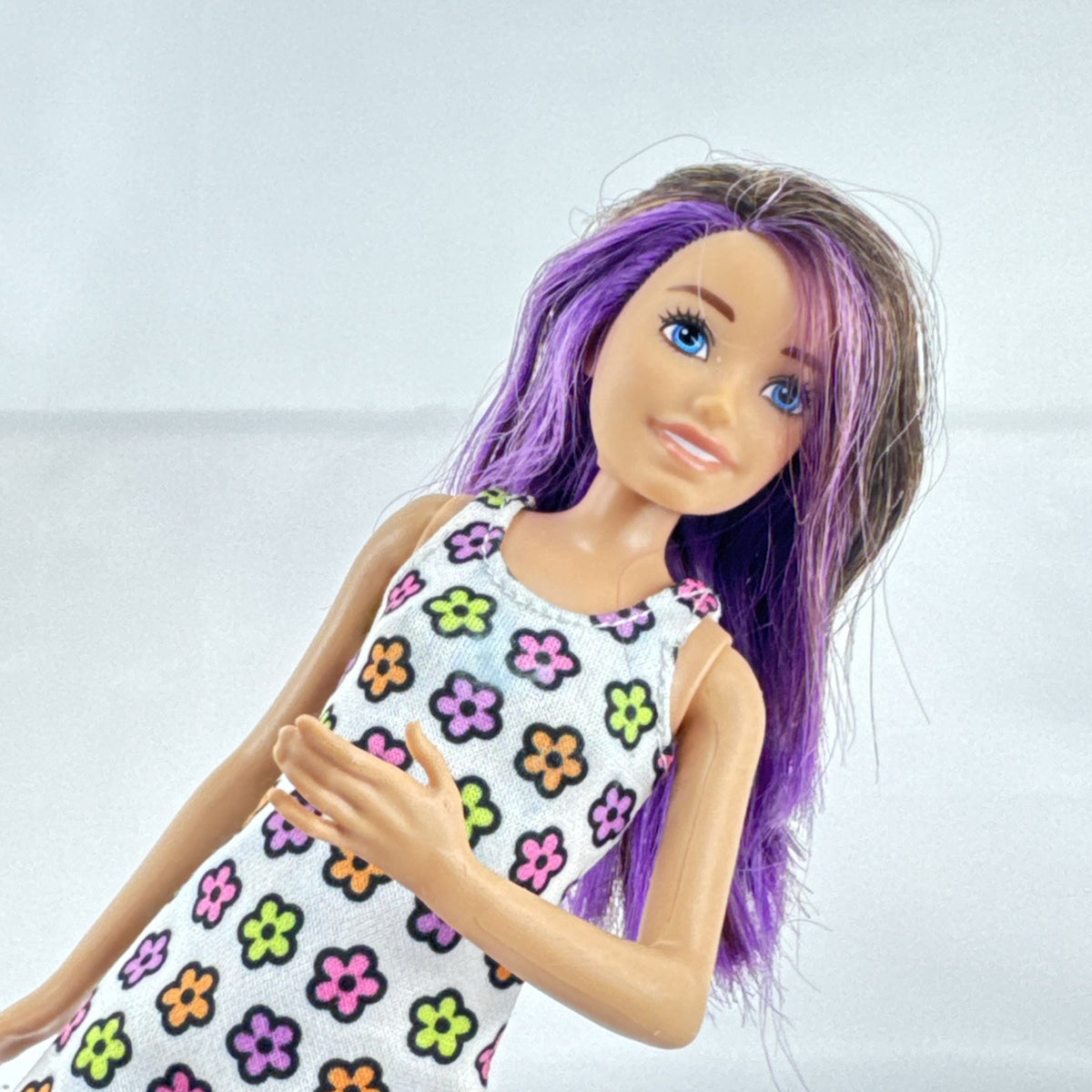 Mattel Barbie Skipper 10-inch doll with purple streaked brown hair in a floral mini dress and pink shoes