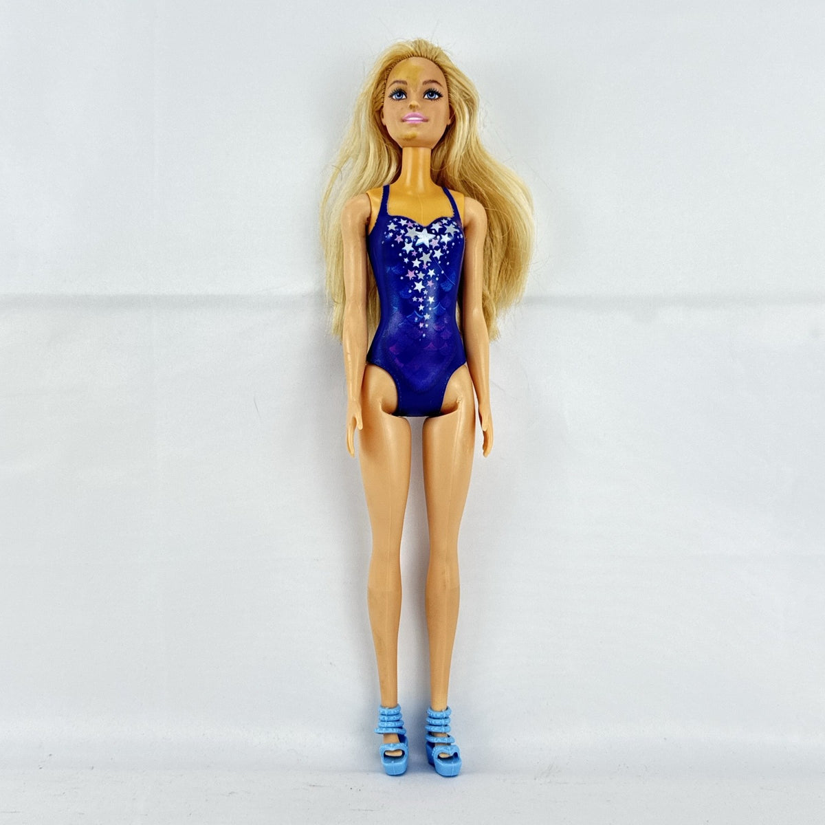 Blonde Mattel Barbie doll wearing a molded blue star swimsuit and matching blue strappy heels