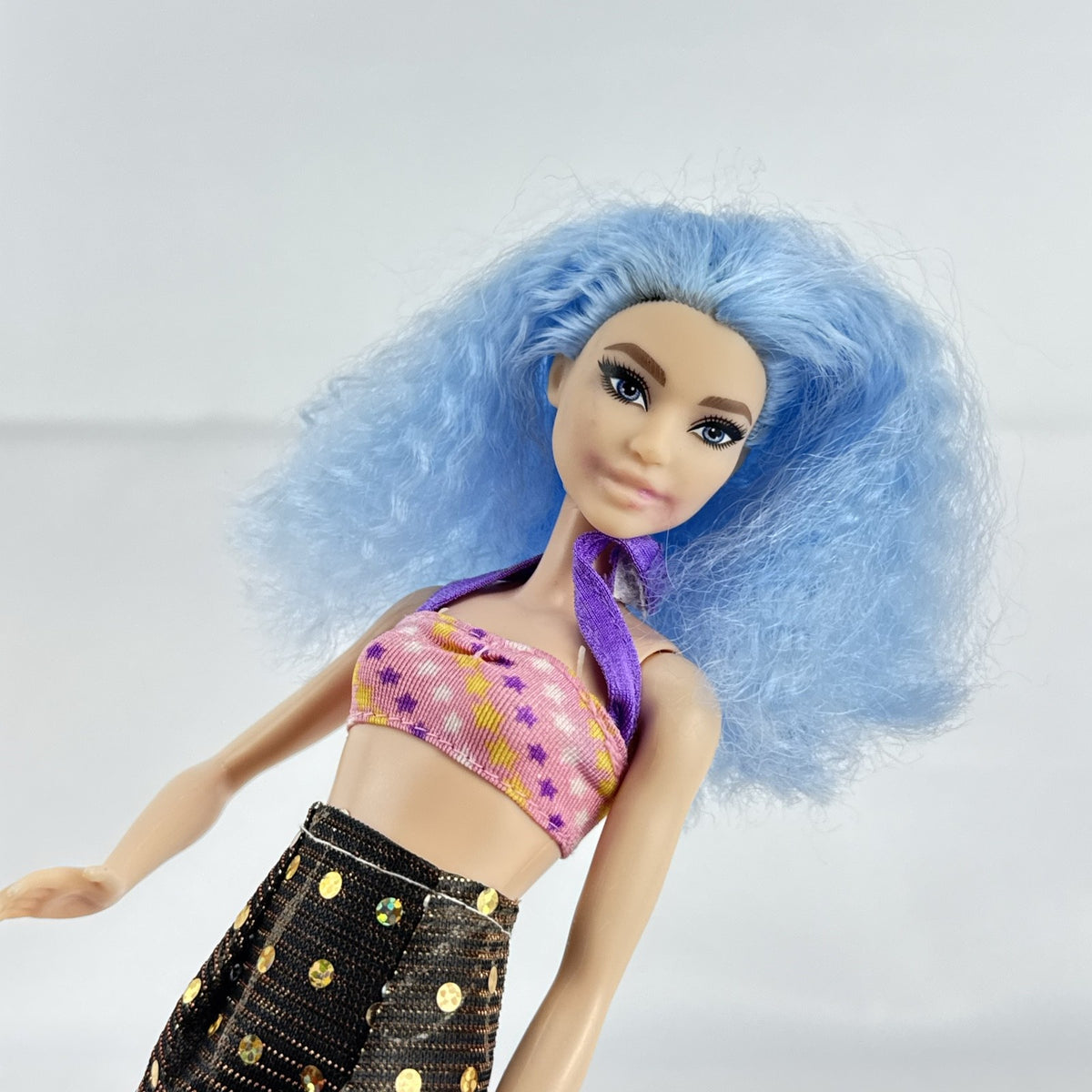 Mattel Barbie Fashionistas 12-inch doll with curly light blue hair, halter crop top, and gold sequin skirt