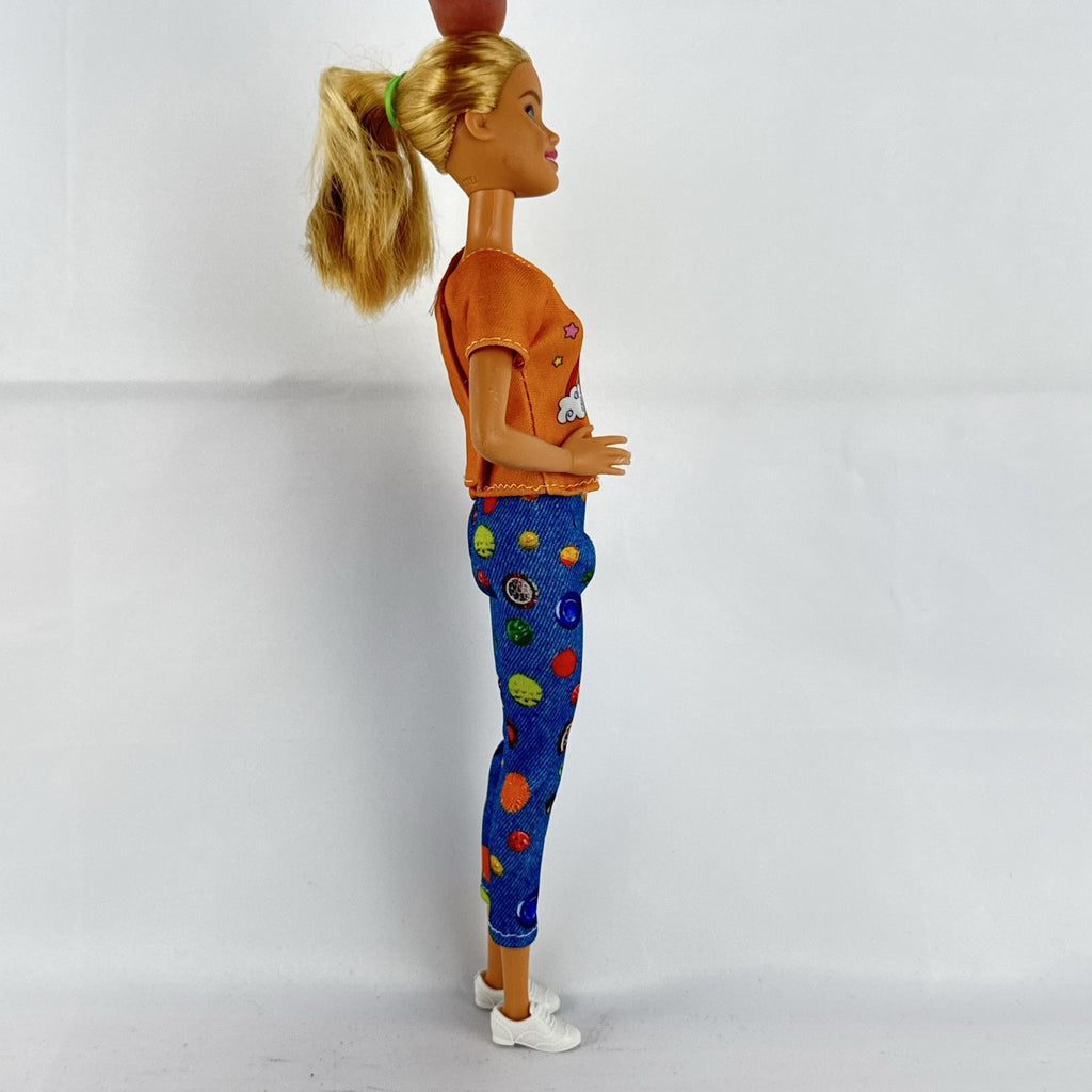 Mattel blonde Barbie doll wearing an orange rainbow shirt, button print pants, and white sneakers.