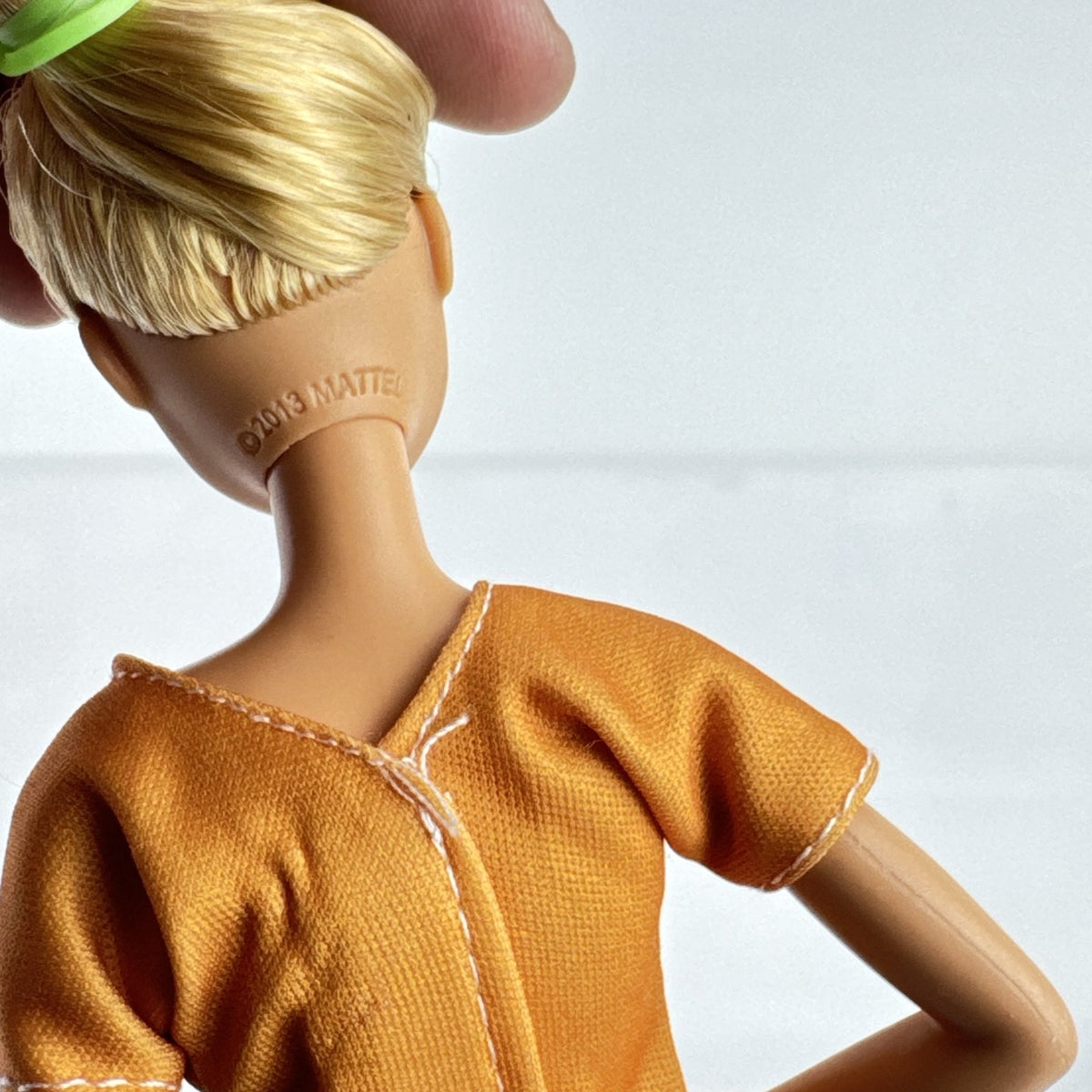 Mattel blonde Barbie doll wearing an orange rainbow shirt, button print pants, and white sneakers.