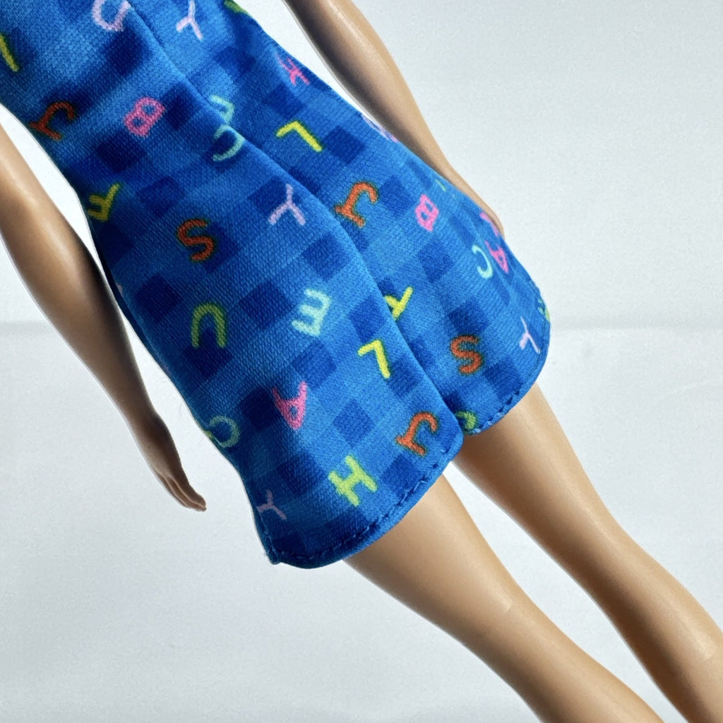 Mattel Barbie Careers teacher doll with blonde hair bun wearing a blue alphabet dress and pink shoes