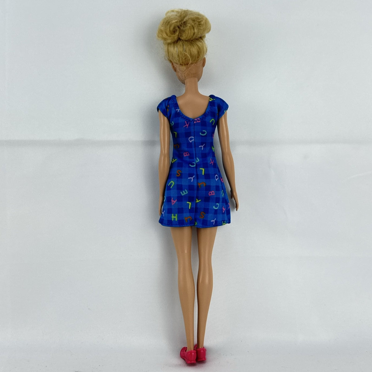 Mattel Barbie Careers teacher doll with blonde hair bun wearing a blue alphabet dress and pink shoes