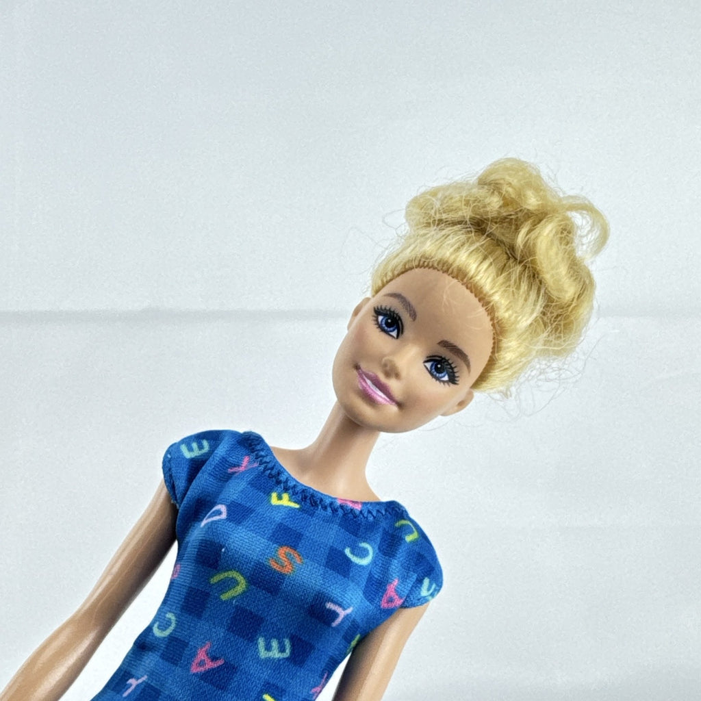 Mattel Barbie Careers teacher doll with blonde hair bun wearing a blue alphabet dress and pink shoes