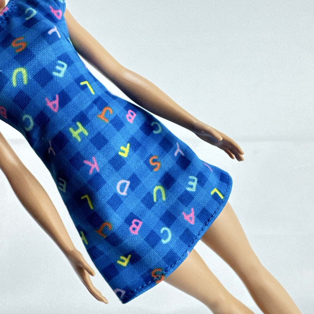 Mattel Barbie Careers teacher doll with blonde hair bun wearing a blue alphabet dress and pink shoes