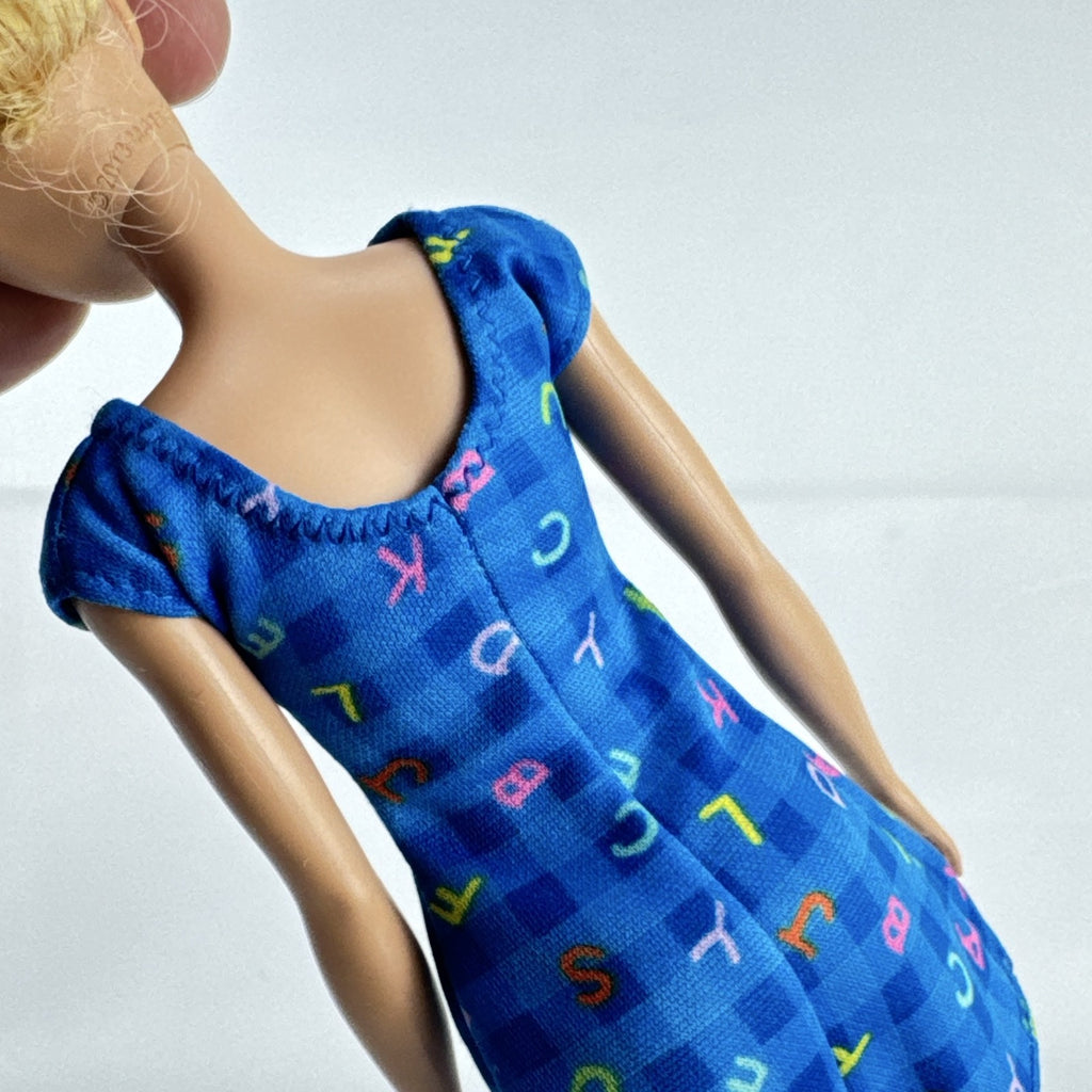 Mattel Barbie Careers teacher doll with blonde hair bun wearing a blue alphabet dress and pink shoes