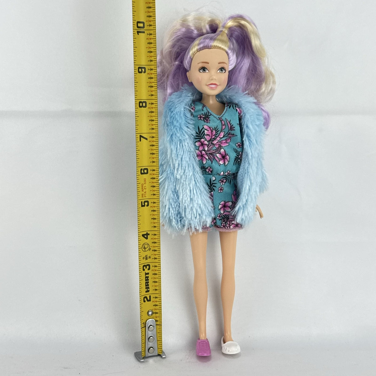 Just Play Hairdorables Hairmazing Harmony fashion doll with purple hair, floral romper, and light blue faux fur vest
