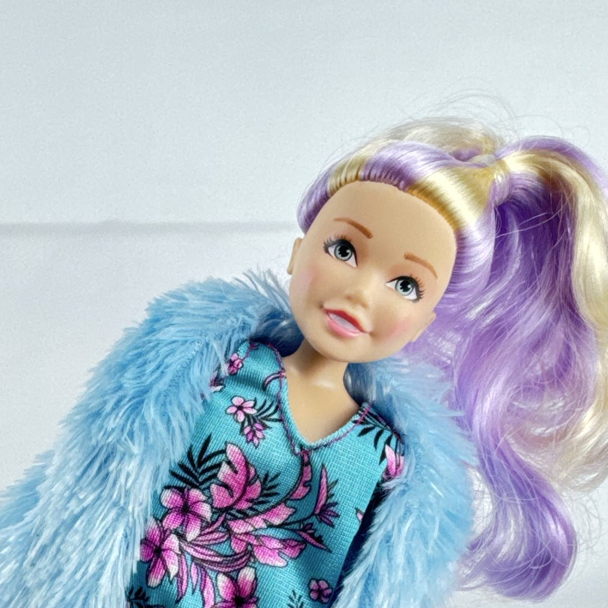 Just Play Hairdorables Hairmazing Harmony fashion doll with purple hair, floral romper, and light blue faux fur vest
