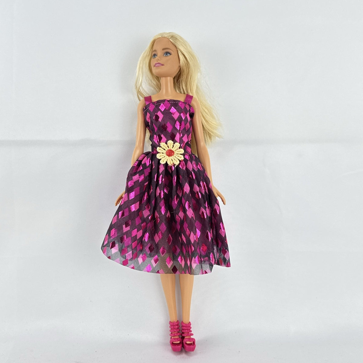Mattel Barbie doll with blonde hair wearing a pink and purple metallic diamond dress with pink high heels