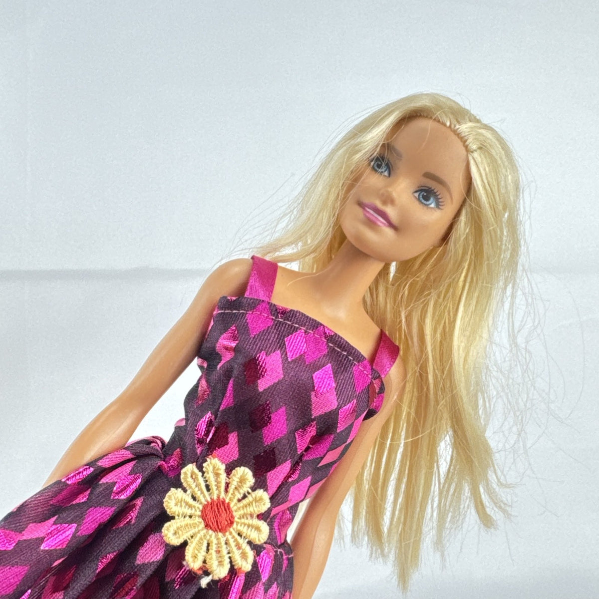 Mattel Barbie doll with blonde hair wearing a pink and purple metallic diamond dress with pink high heels