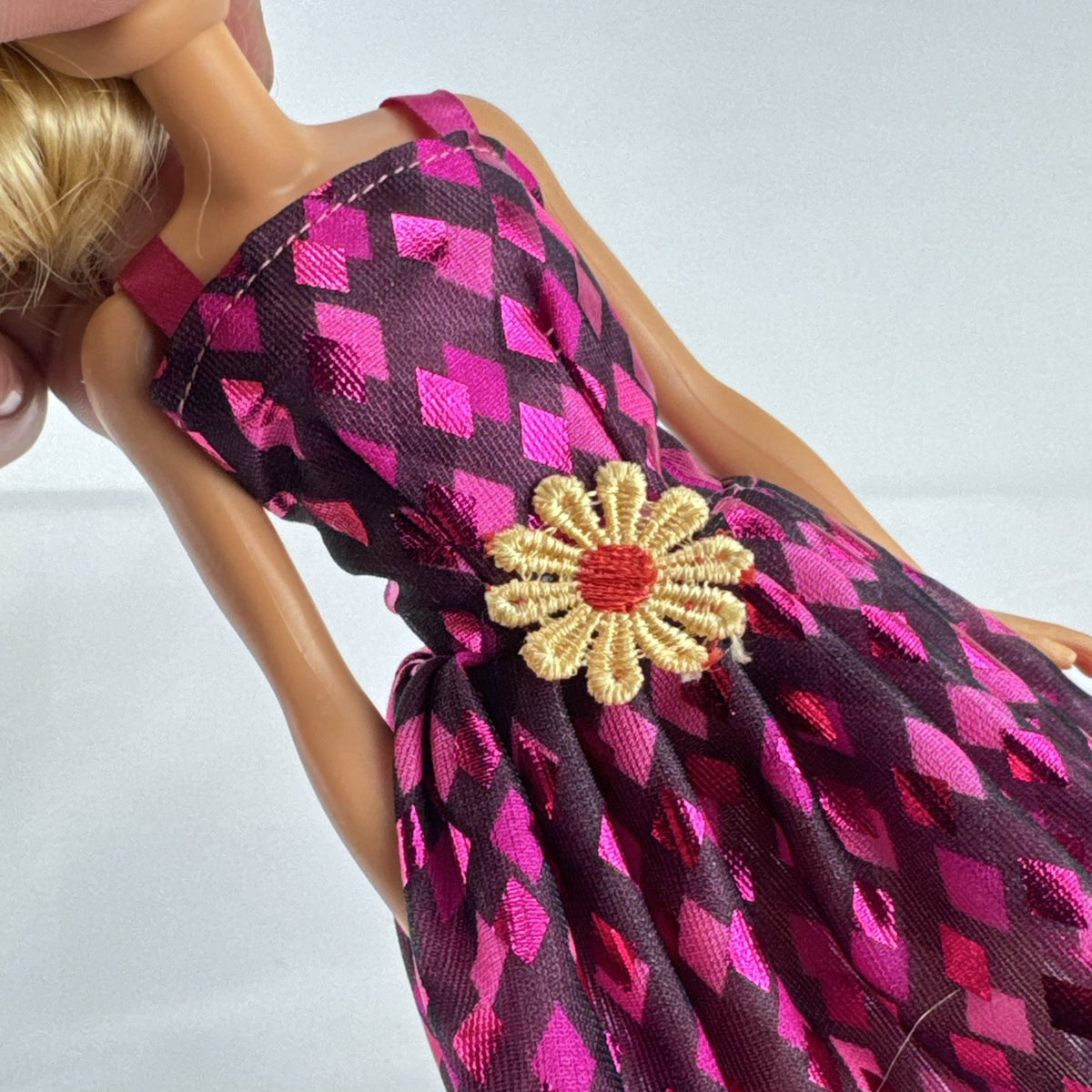 Mattel Barbie doll with blonde hair wearing a pink and purple metallic diamond dress with pink high heels