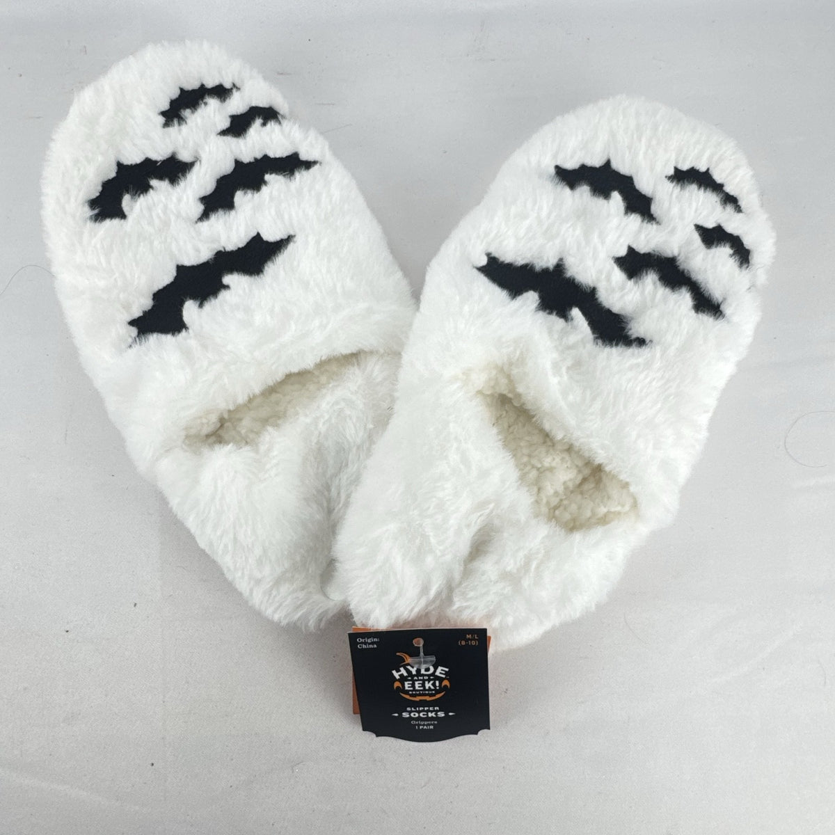 Hyde & EEK! Boutique ivory faux-fur slipper socks with black bat silhouettes and non-slip treads in women's size M/L.