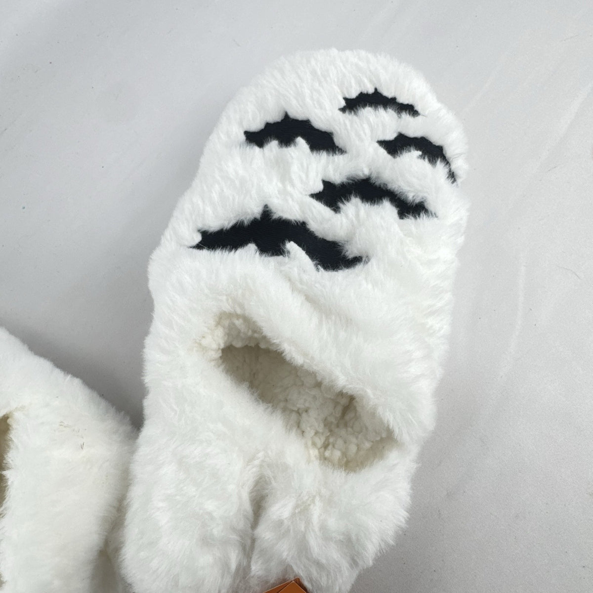 Hyde & EEK! Boutique ivory faux-fur slipper socks with black bat silhouettes and non-slip treads in women's size M/L.