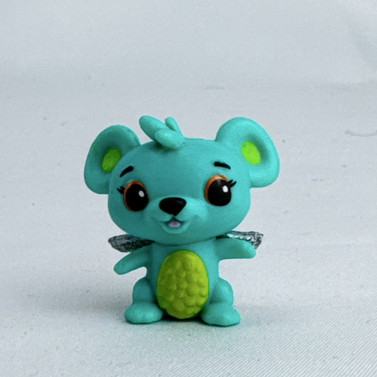 Spin Master Hatchimals CollEGGtibles mini figure in teal and lime green with silver glitter wings.