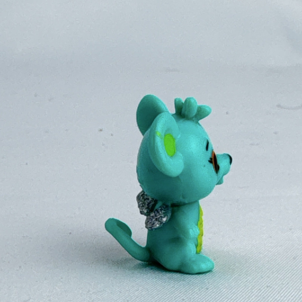 Spin Master Hatchimals CollEGGtibles mini figure in teal and lime green with silver glitter wings.