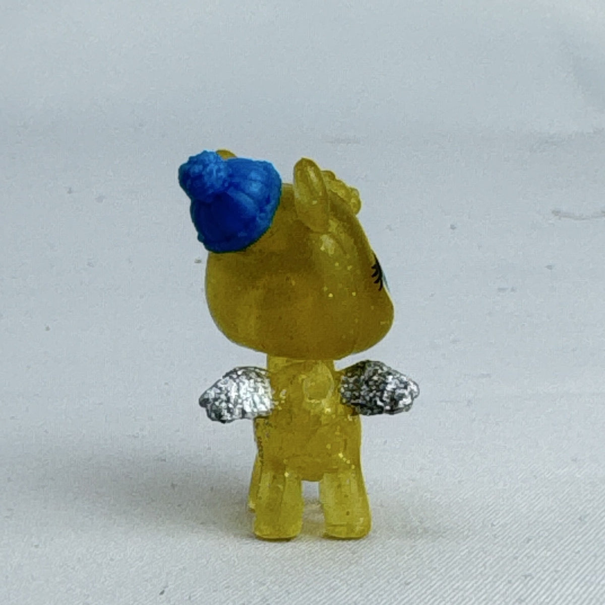 Spin Master Hatchimals CollEGGtibles translucent yellow glitter griffin mini figure wearing a blue winter beanie