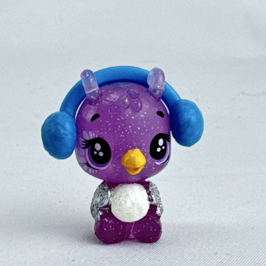 Spin Master Hatchimals CollEGGtibles miniature purple glitter penguin figure wearing molded blue earmuffs.