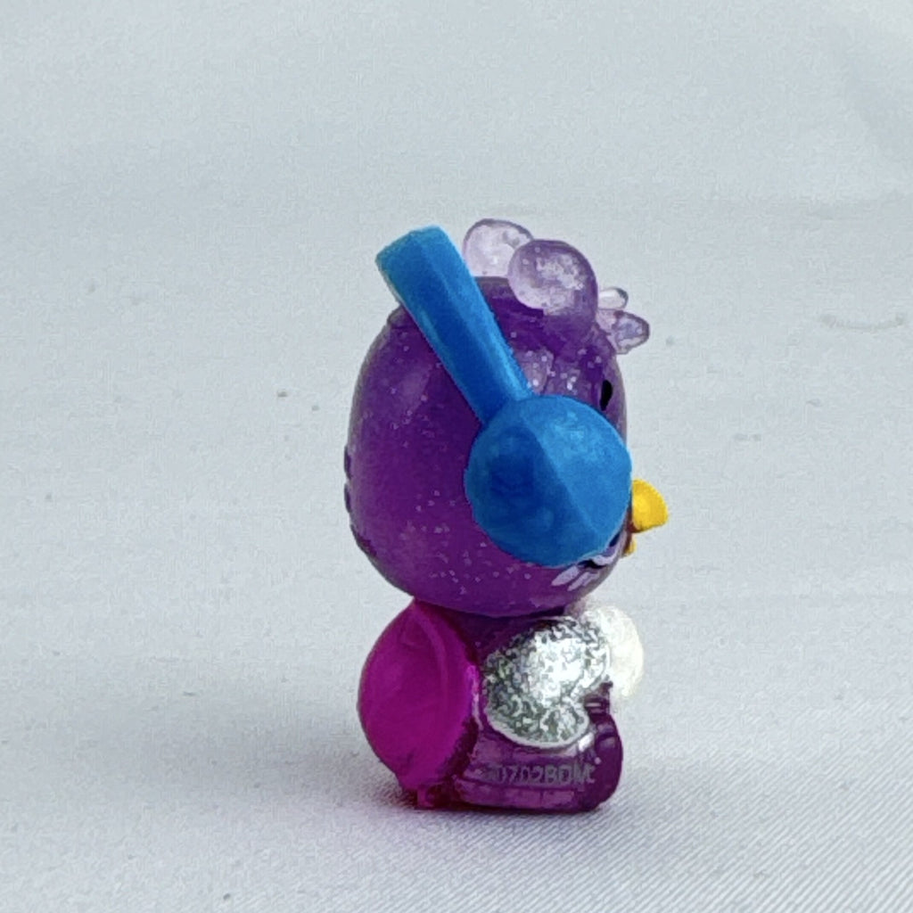 Spin Master Hatchimals CollEGGtibles miniature purple glitter penguin figure wearing molded blue earmuffs.