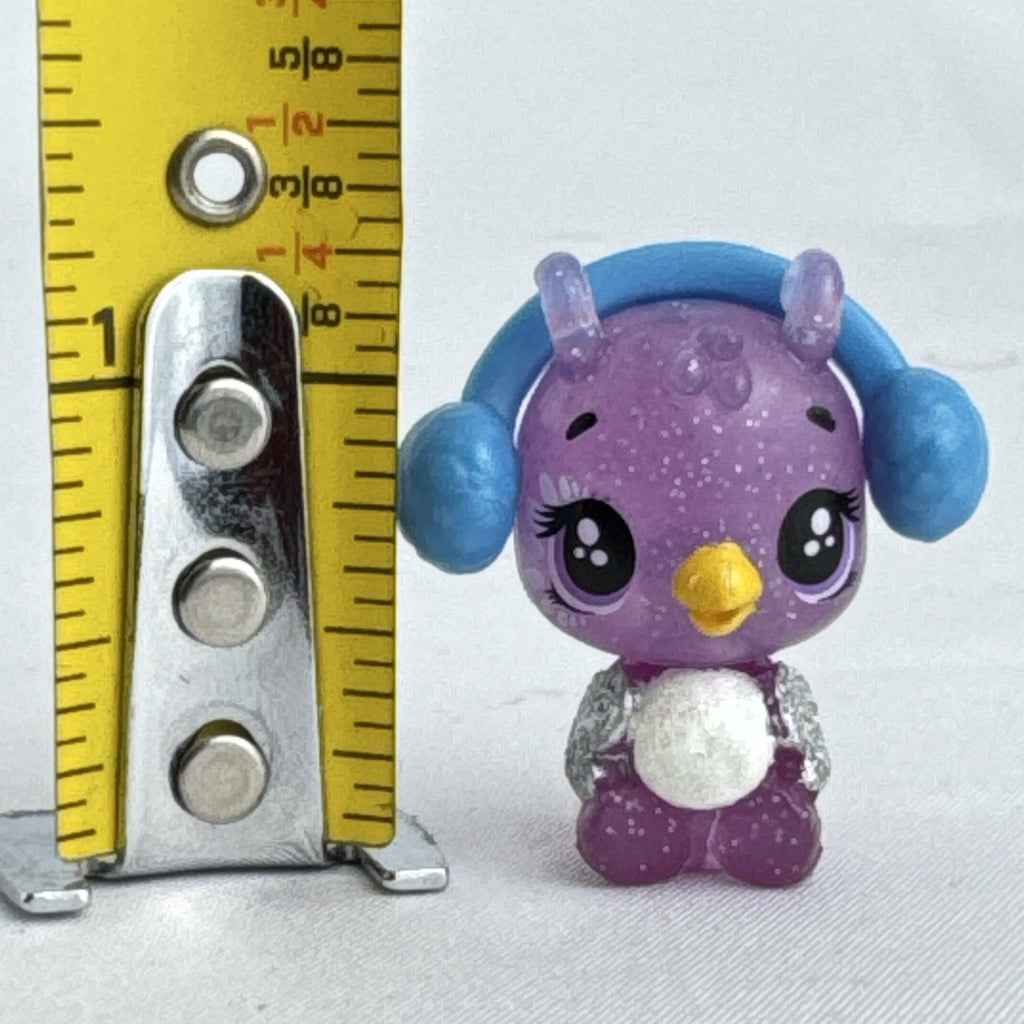 Spin Master Hatchimals CollEGGtibles miniature purple glitter penguin figure wearing molded blue earmuffs.