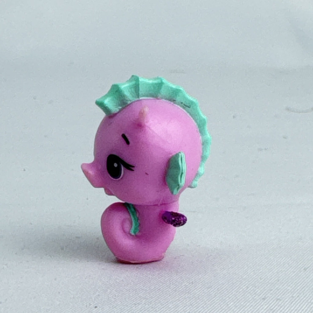 Spin Master Hatchimals Colleggtibles miniature pink seahorse figure with mint green accents and purple glitter wings.