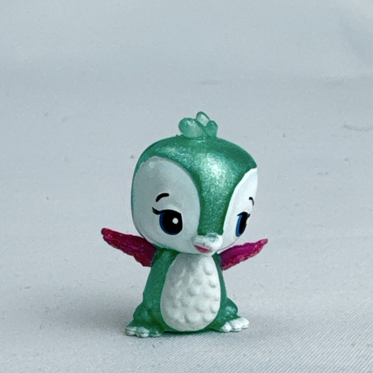Mattel Barbie Dreamtopia miniature green shimmer penguin pet figure with pink glitter wings.
