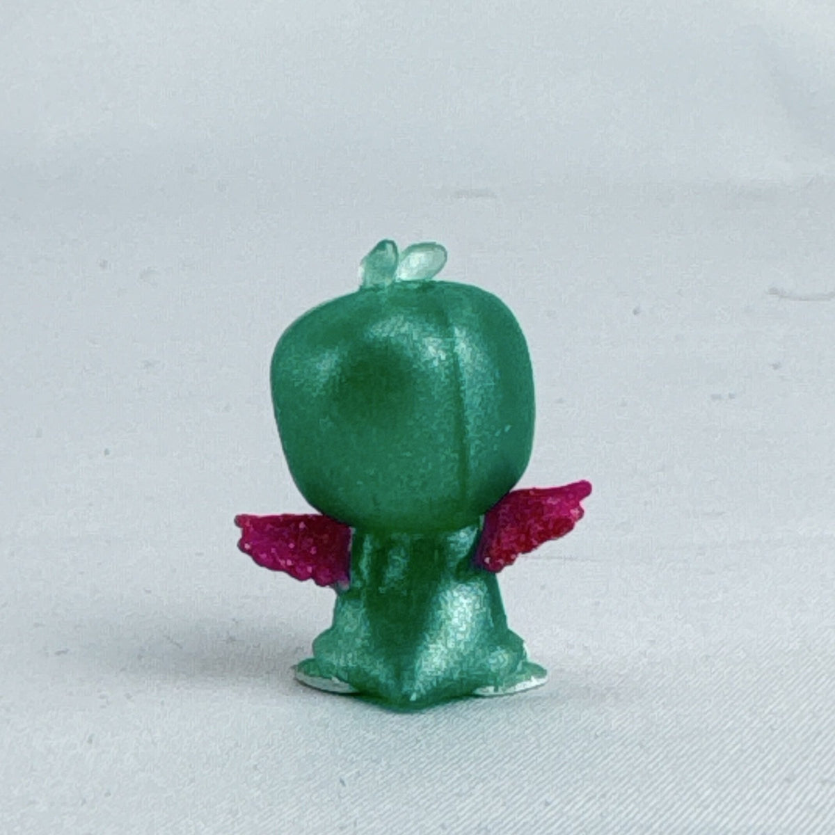 Mattel Barbie Dreamtopia miniature green shimmer penguin pet figure with pink glitter wings.