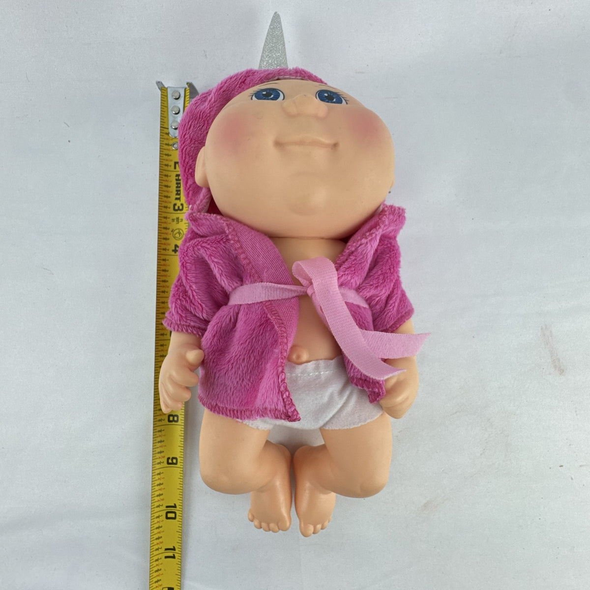 Cabbage Patch Kids 9-inch vinyl baby doll wearing a hooded pink unicorn robe with silver horn