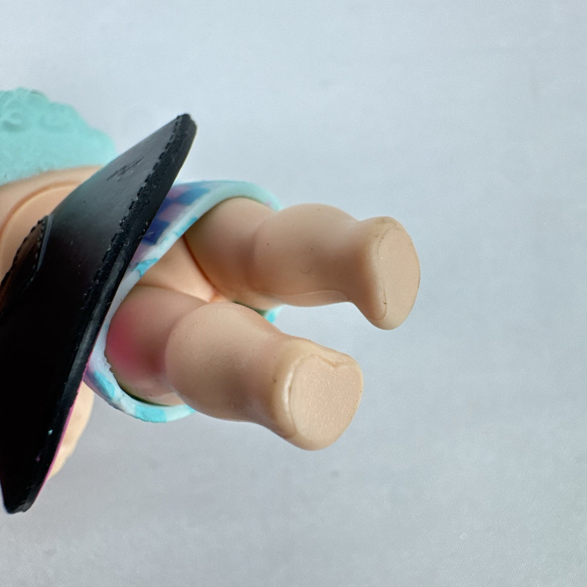 MGA Entertainment L.O.L. Surprise! The Great Baby doll with curly turquoise hair, top hat headband, and black cape.