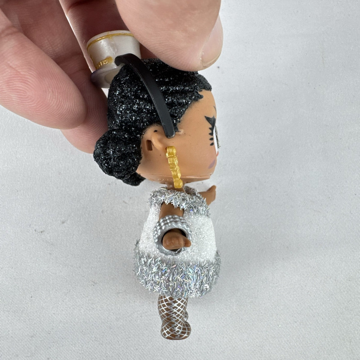 MGA L.O.L. Surprise 3-inch doll with black glitter hair buns and silver tinsel dress