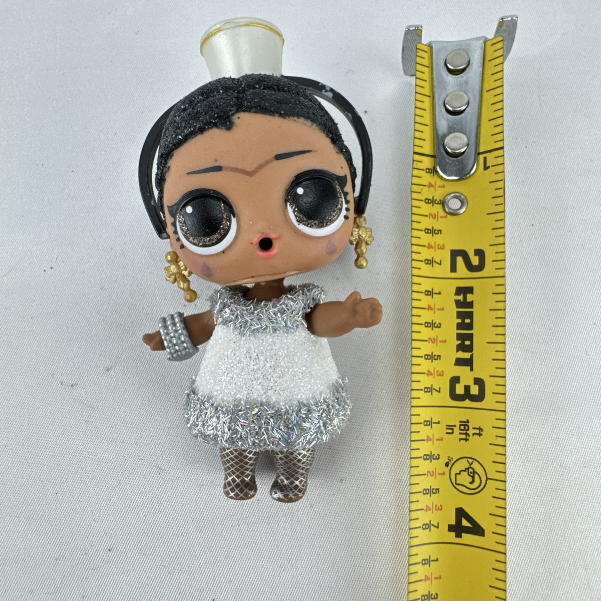 MGA L.O.L. Surprise 3-inch doll with black glitter hair buns and silver tinsel dress