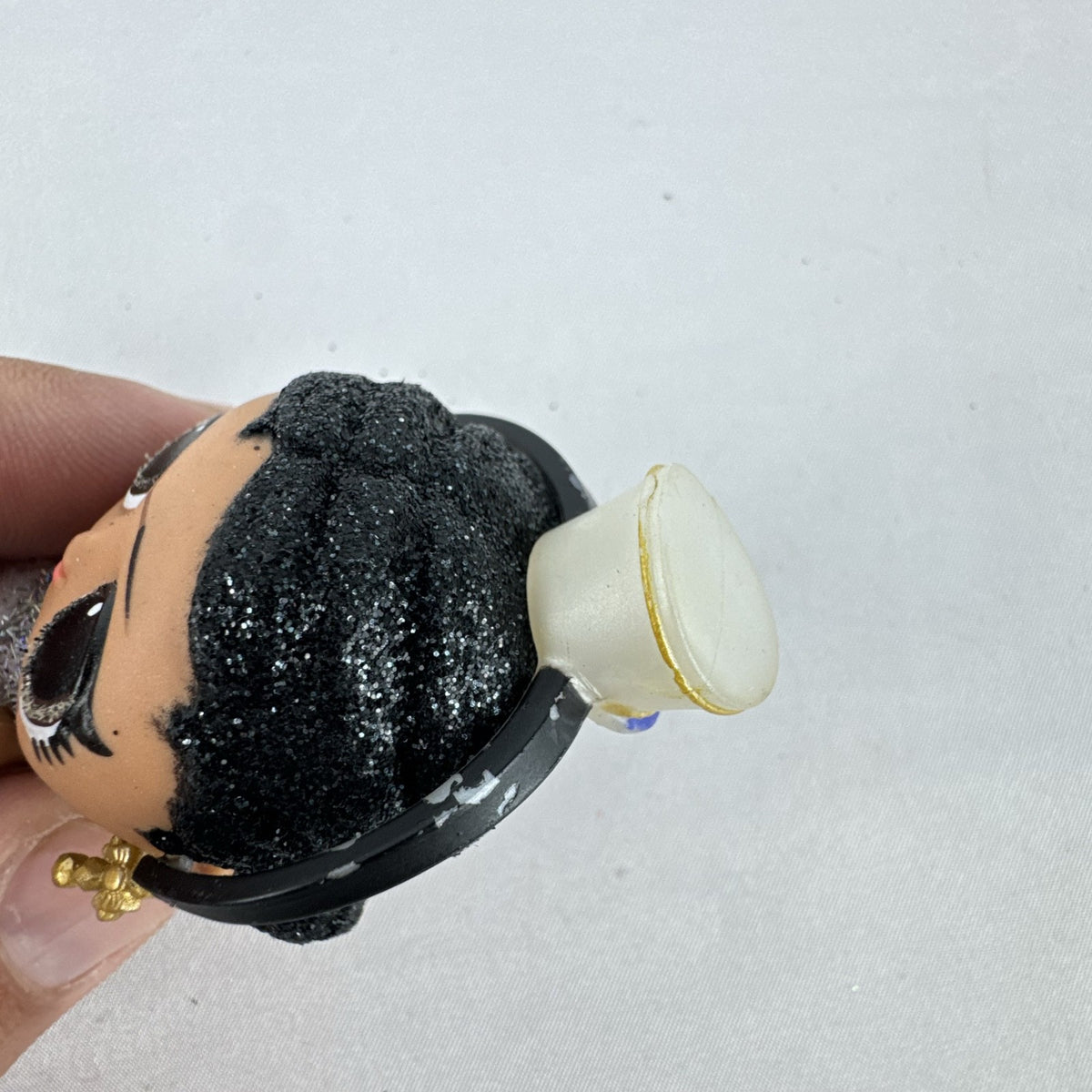 MGA L.O.L. Surprise 3-inch doll with black glitter hair buns and silver tinsel dress