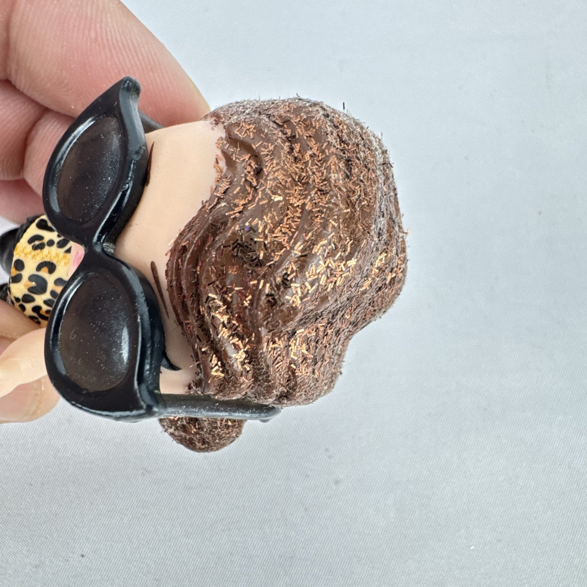 MGA L.O.L. Surprise! 3-inch doll wearing leopard print outfit, cat-eye sunglasses, and boots with brown glitter hair