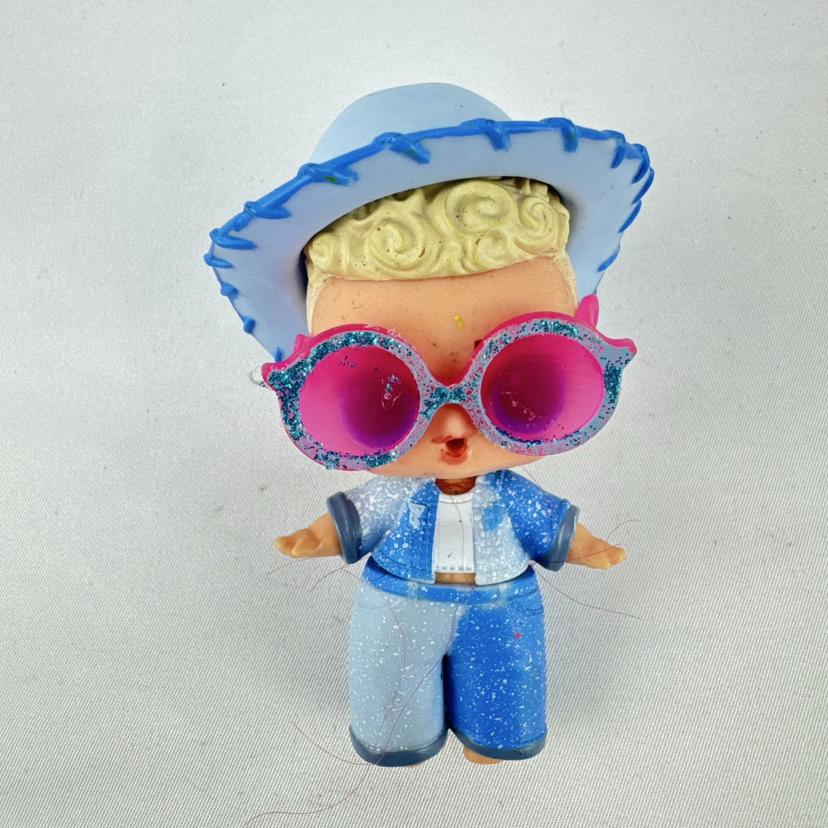 MGA L.O.L. Surprise! Boys Series 1 Do-Si-Dude 3-inch doll wearing blue cowboy hat and pink sunglasses