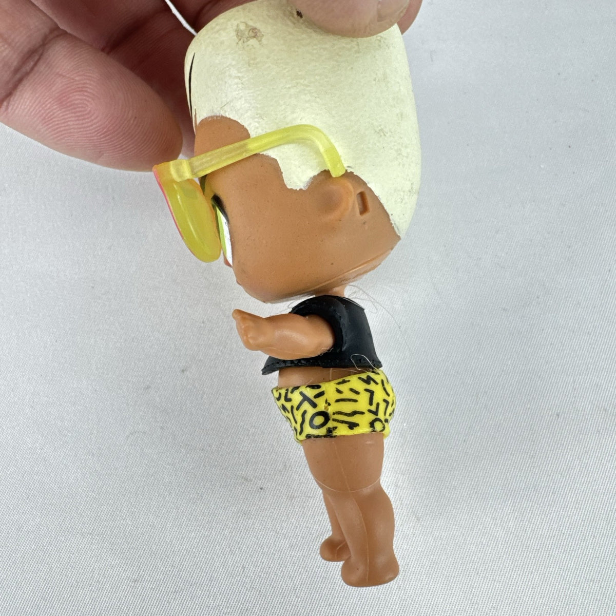 MGA Entertainment L.O.L. Surprise! 3-inch mini doll with blonde flat-top hair, sunglasses, and BAD crop top