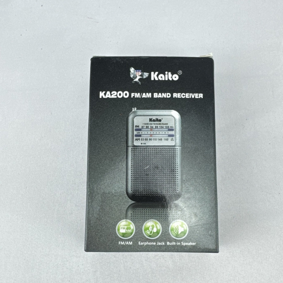 Gray Kaito KA200 pocket AM FM radio with analog dial and headphone jack in original packaging
